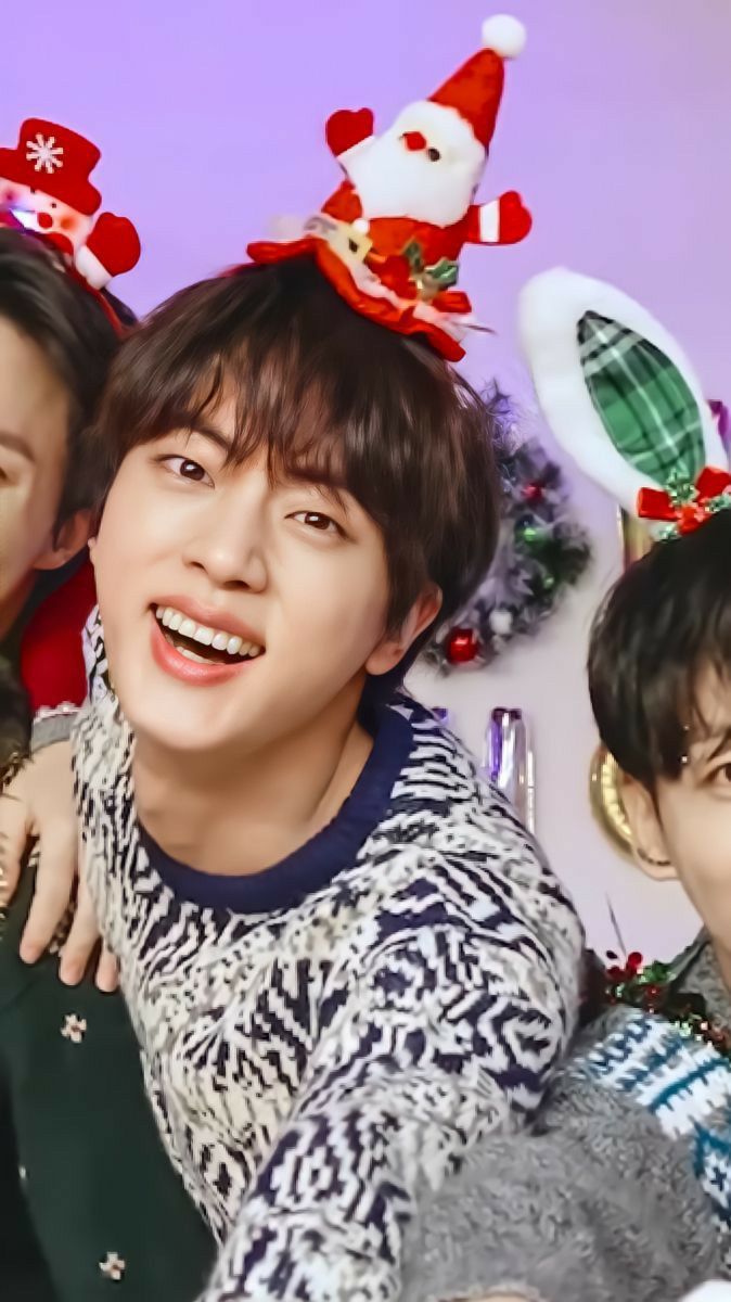 three young people are posing for a photo with christmas decorations on the wall behind them