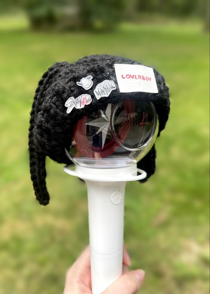 a person holding up a black hat on top of a white pole