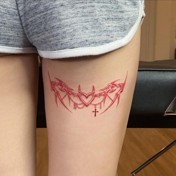 a woman's leg with a tattoo on it that has two bats in the shape of a heart