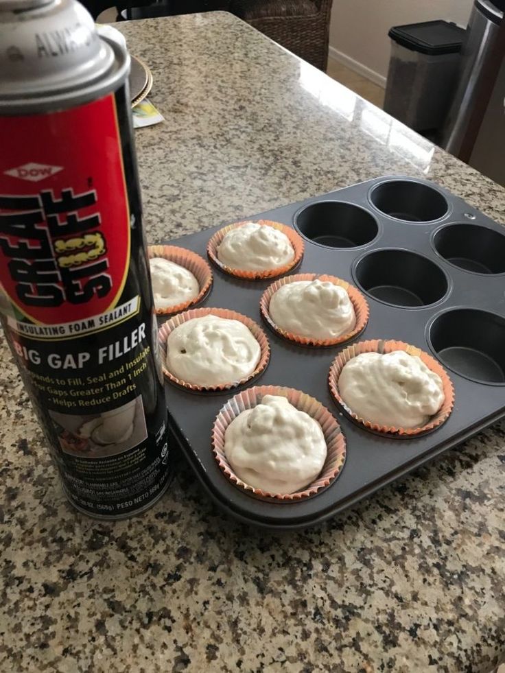 cupcakes with white frosting sitting in a muffin tin next to a can of baking soda