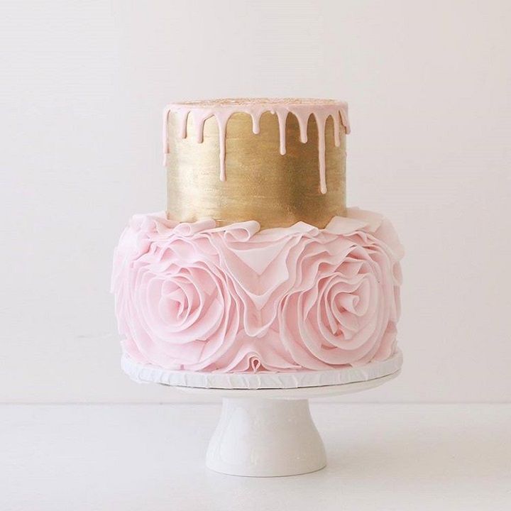 a pink and gold cake sitting on top of a white pedestal