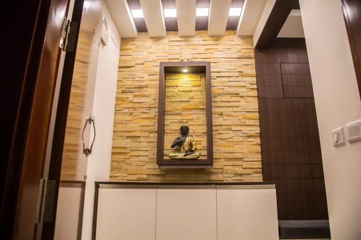 a room with a stone wall and white cabinet in the center, along with a large mirror on the wall