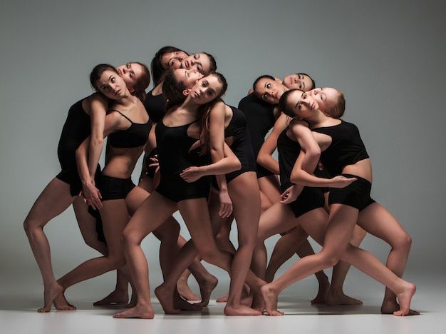 a group of young women in black leotards posing for the camera with their arms around each other