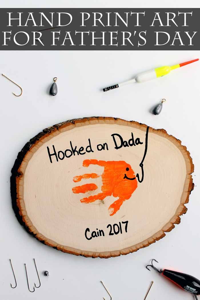 handprint art for father's day is displayed on a wood slice with fishing hooks