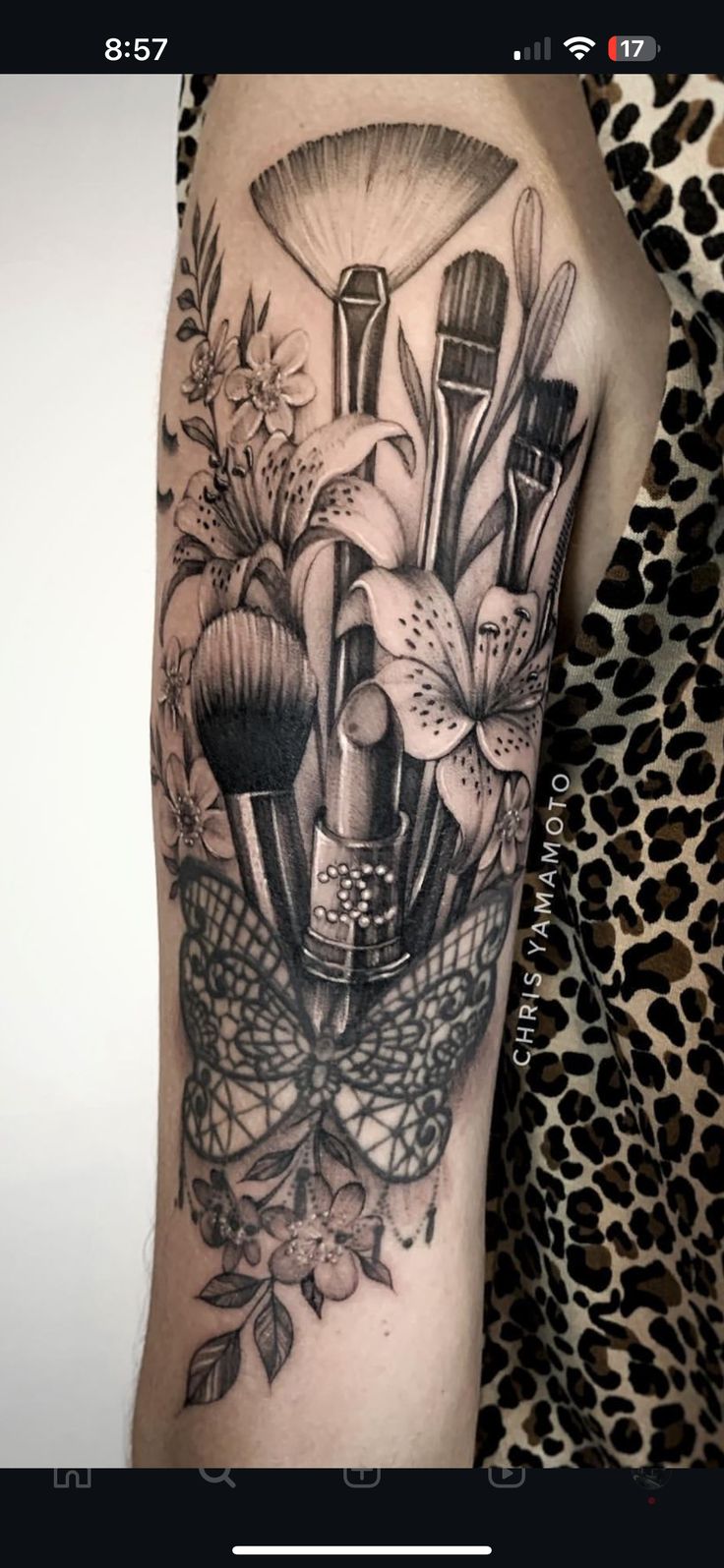 a woman's arm with a black and white tattoo on it, including brushes and flowers