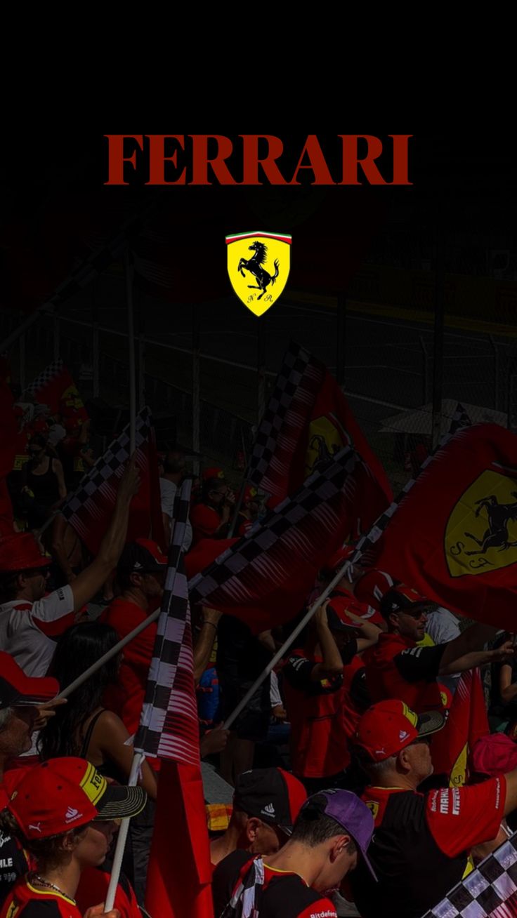 ferrari fans waving their red and black flags at night in front of the team's logo