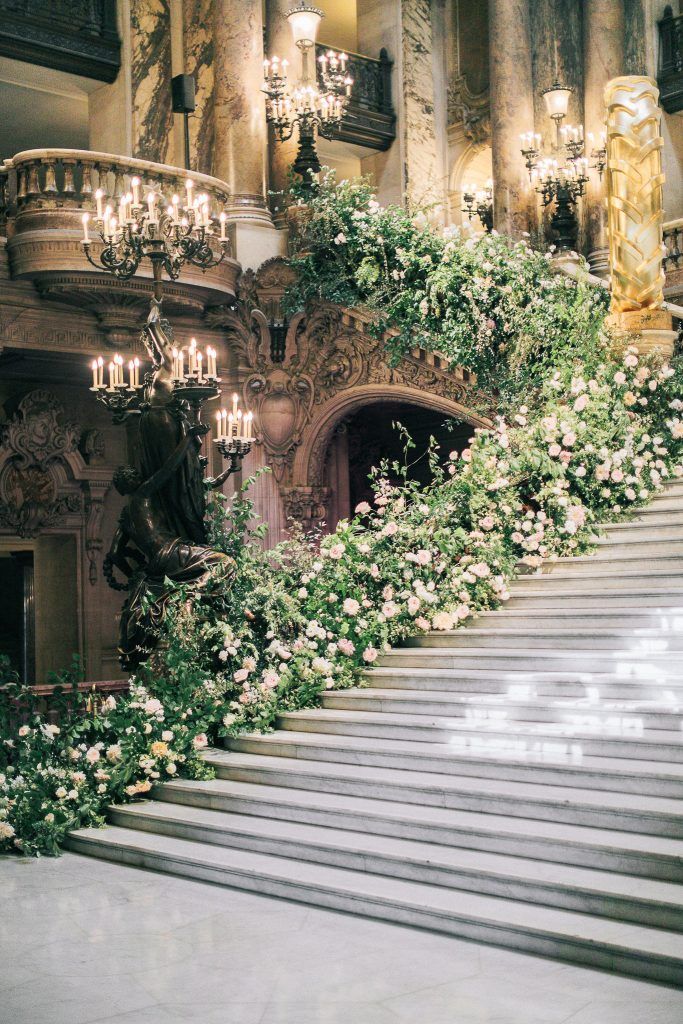 an elaborate staircase with flowers and chandeliers on the sides, leading up to a statue