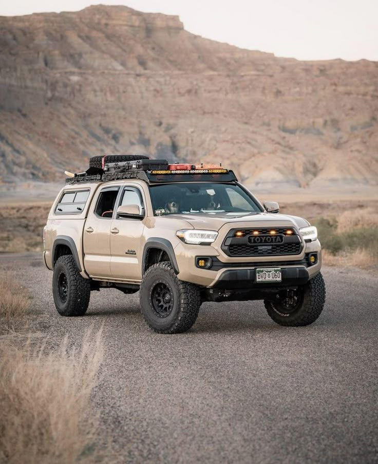 the truck is parked on the side of the road in front of a mountain range