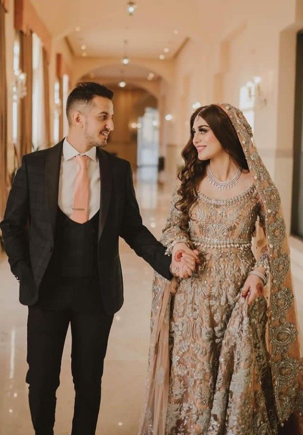 a bride and groom walking down the hall holding hands