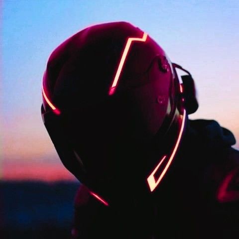 a person wearing a helmet with neon lights on their face and back, in front of a sunset