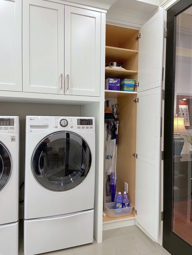 a washer and dryer in a room with white cupboards on the wall