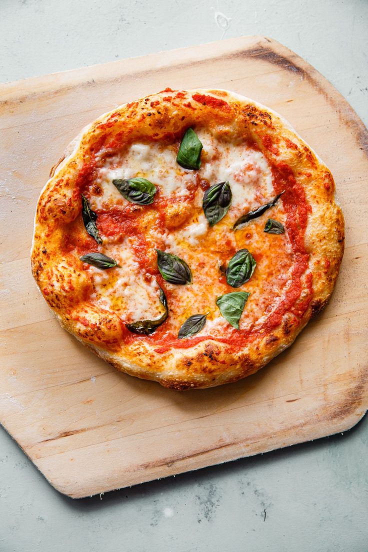 a pizza sitting on top of a cutting board covered in cheese and spinach leaves