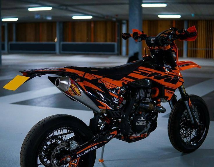 an orange and black dirt bike parked in a parking garage with no one around it