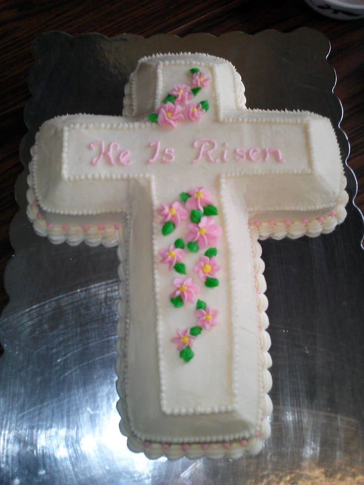 a cake that is shaped like a cross with pink flowers on it and the words he is risen