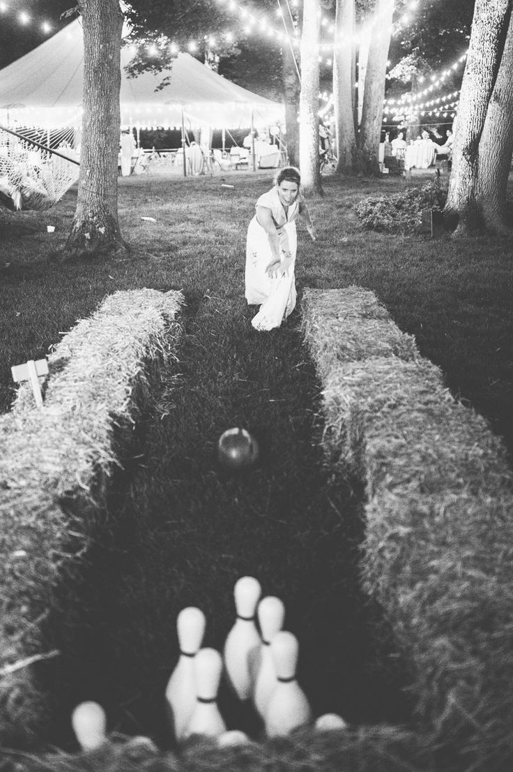 black and white photograph of woman kneeling down in front of bowling pins on the ground