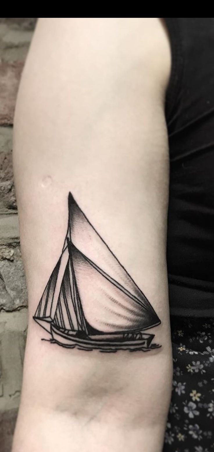 a small black and white sailboat tattoo on the arm