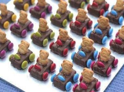 many small teddy bears are sitting on toy cars made out of chocolates and candy