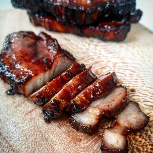 sliced meat sitting on top of a wooden cutting board next to another piece of meat