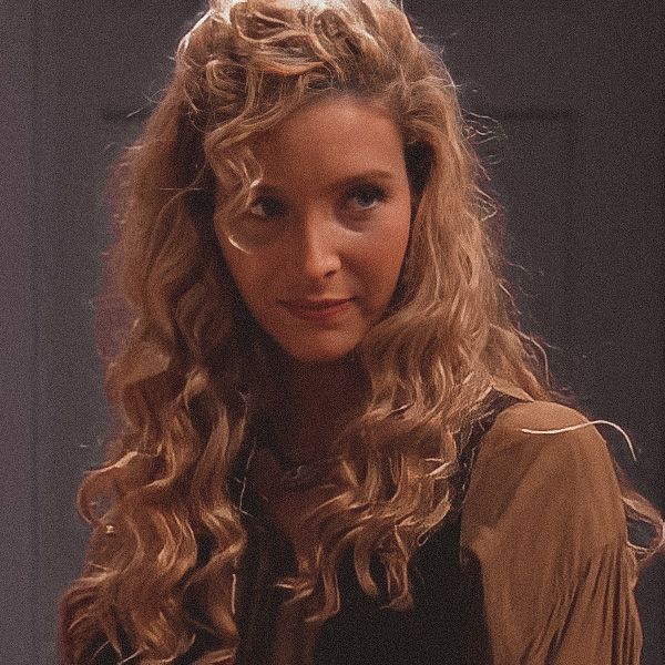 a woman with long curly hair standing in front of a door wearing a brown shirt