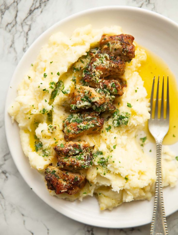 a white plate topped with mashed potatoes and meatballs