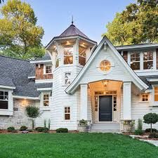 a white house with lots of windows and green grass in front of the door is surrounded by trees