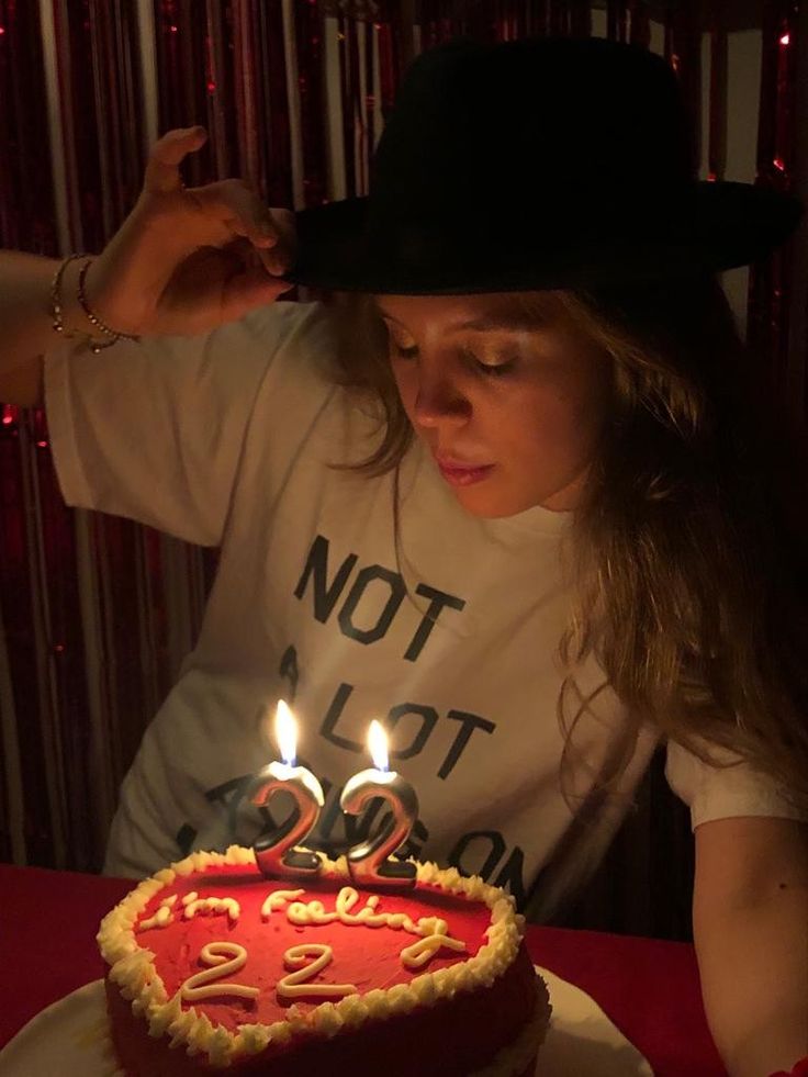 a woman wearing a hat blowing out candles on a birthday cake with the number twenty two