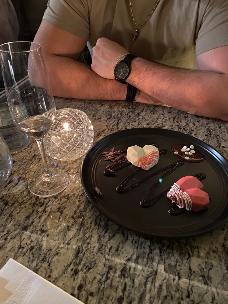 a man sitting at a table with his arms crossed in front of desserts and wine glasses