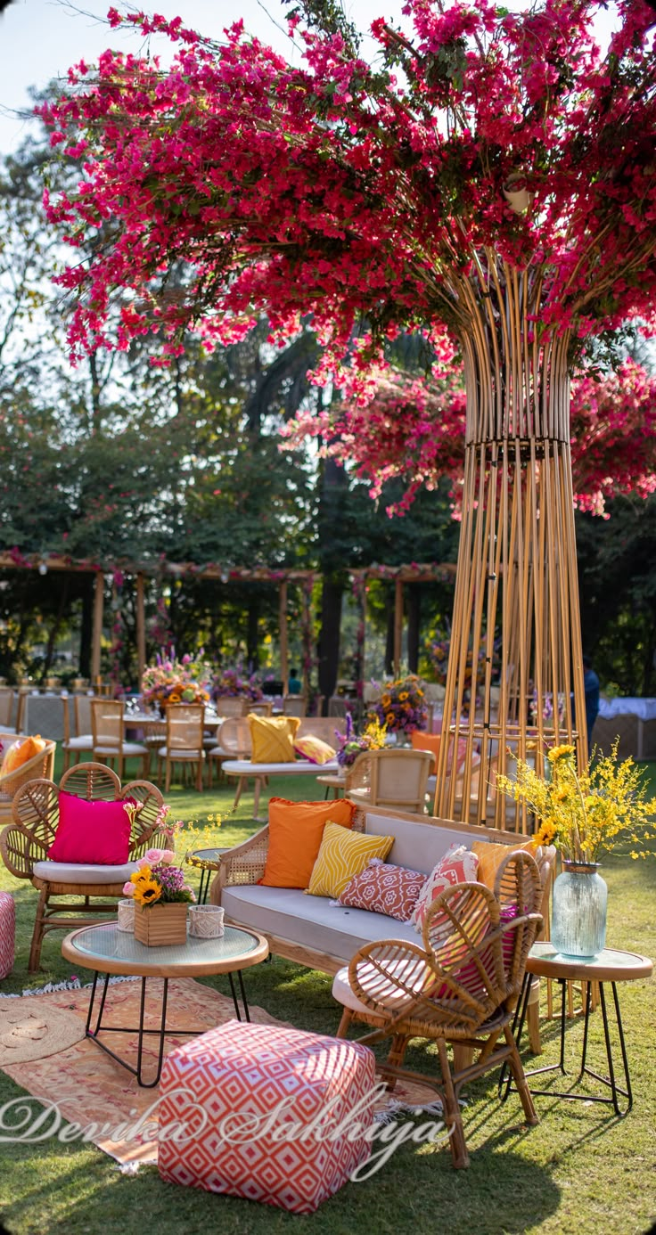 an outdoor seating area with wicker furniture and pink flowers on the trees in the background