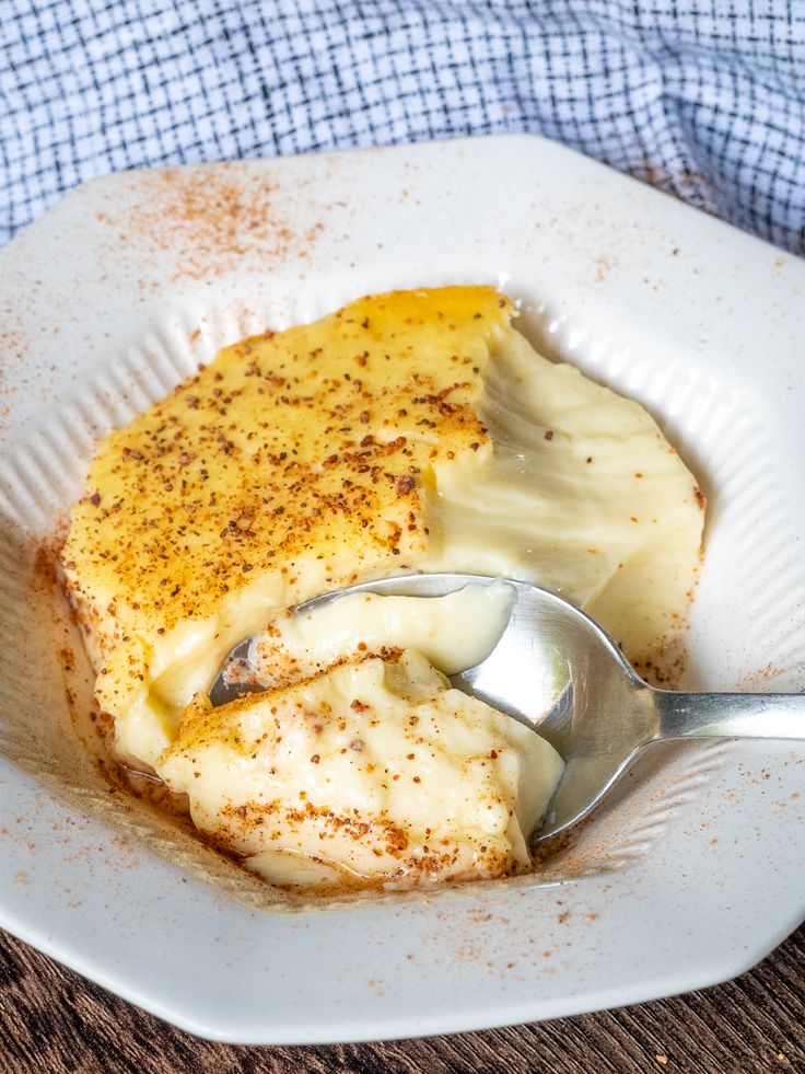 a white plate topped with mashed potatoes and gravy on top of a wooden table