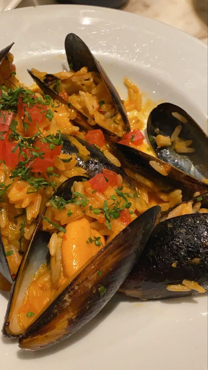 a white plate topped with mussels and rice