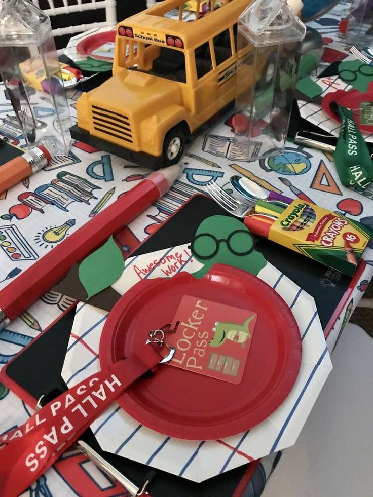 a school bus is on the table next to some paper plates and pencils, pens and markers