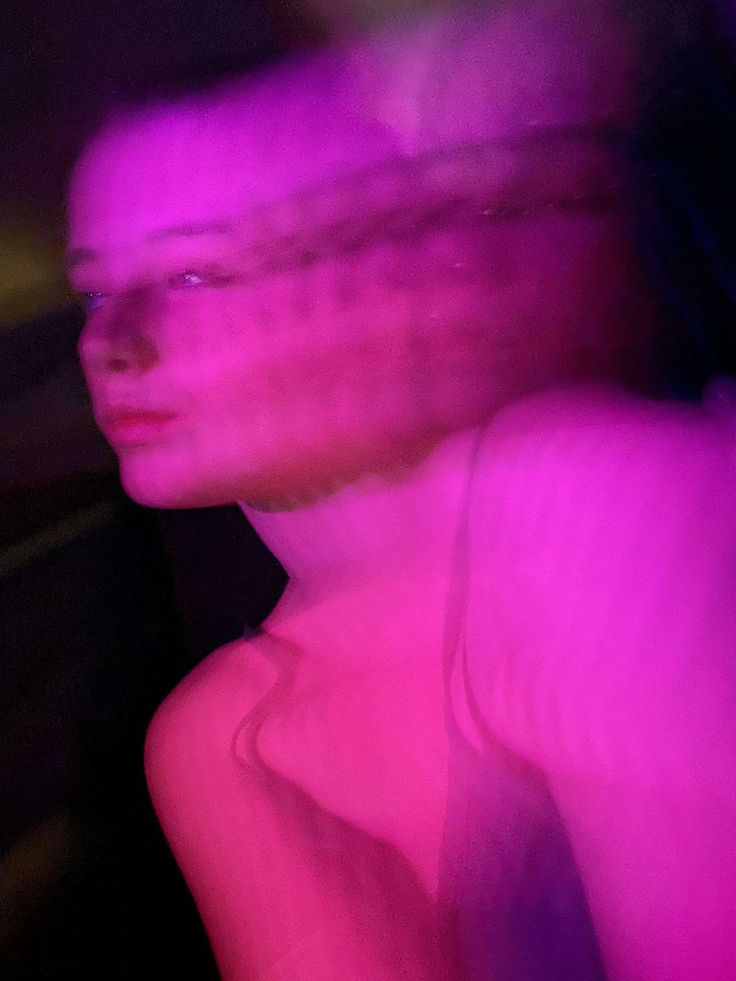 a blurry image of a woman's face and body in purple light,