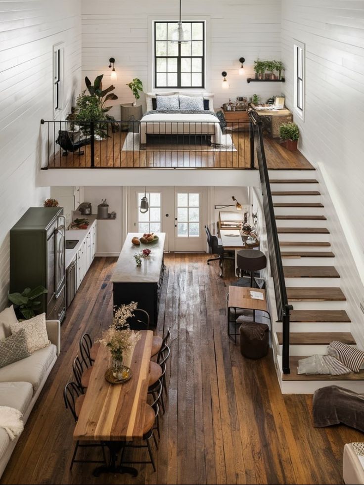 an open floor plan with white walls and wood floors, stairs leading up to the loft