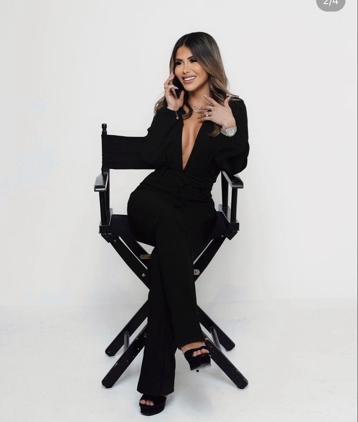 a woman sitting in a black chair talking on a cell phone and smiling at the camera