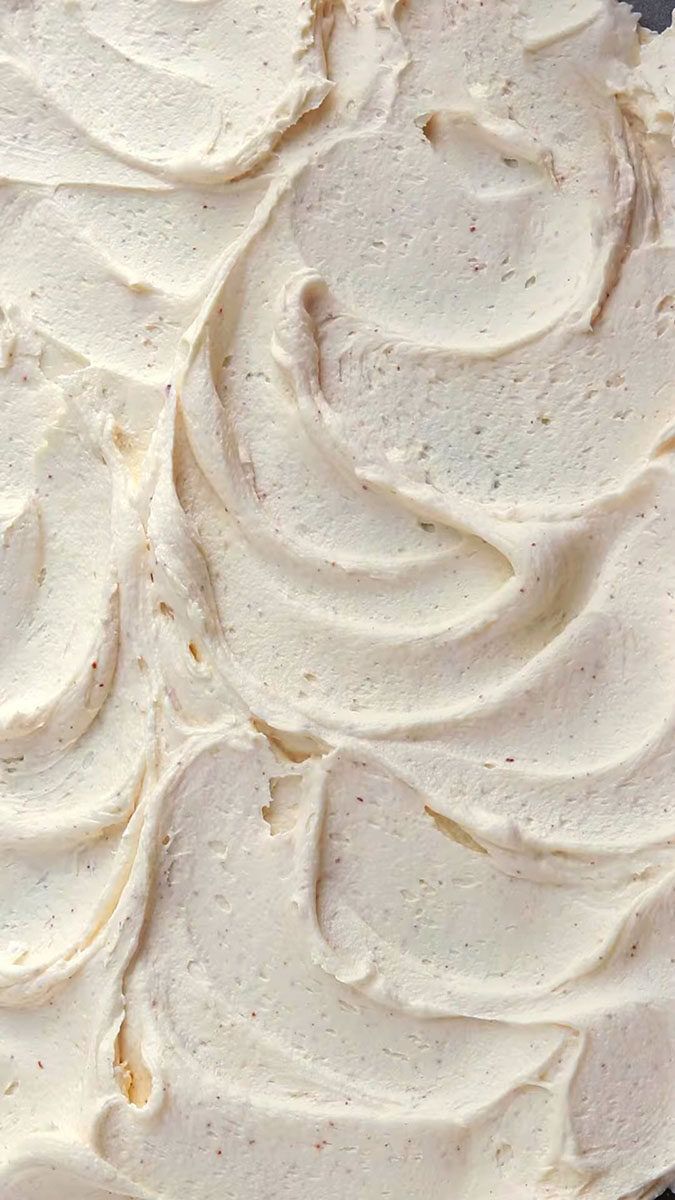 a cake with white frosting sitting on top of a pan covered in icing