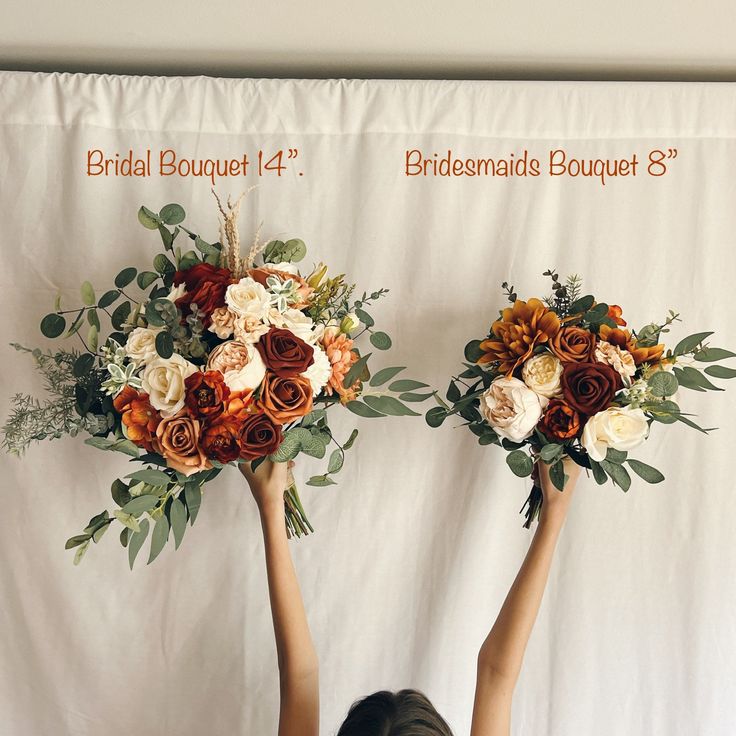 two brides holding their bouquets in front of a white backdrop with orange and red flowers