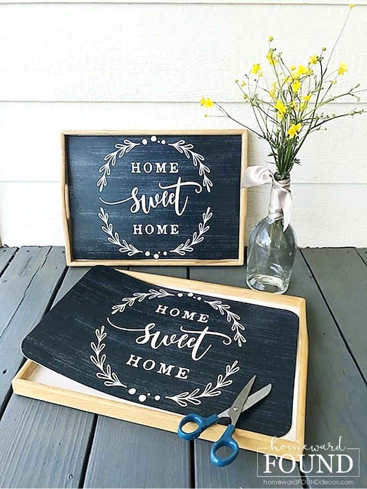 two wooden signs sitting on top of a table next to scissors and vase with flowers