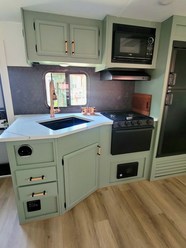 a kitchen with green cabinets and black appliances