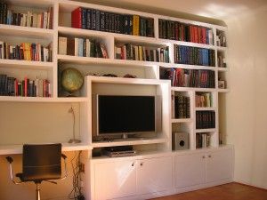 a living room with bookshelves and a television on top of the entertainment center