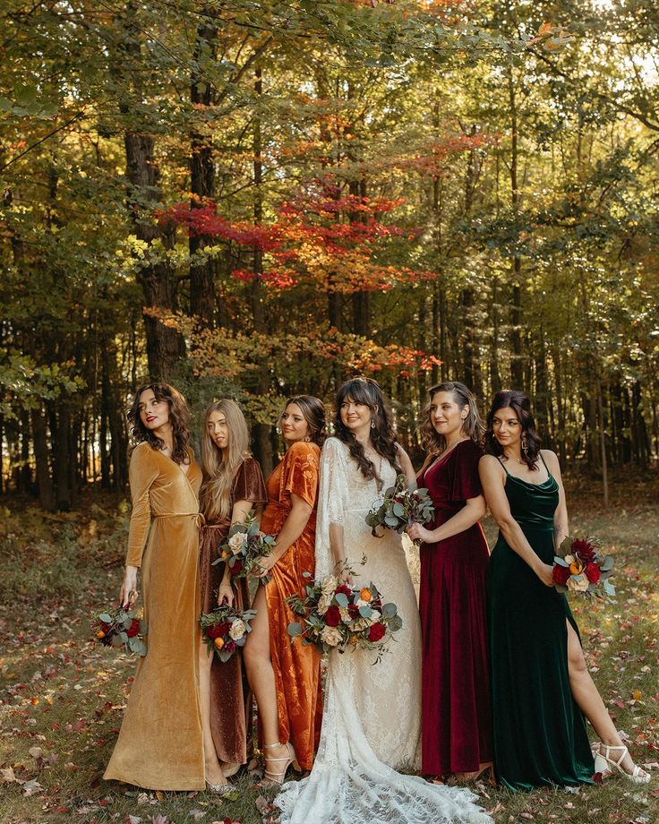 a group of women standing next to each other in front of trees with leaves on the ground