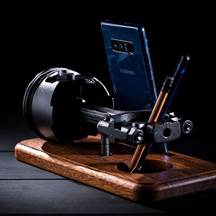 a cell phone is sitting on top of a wooden device holder with two screwdrivers