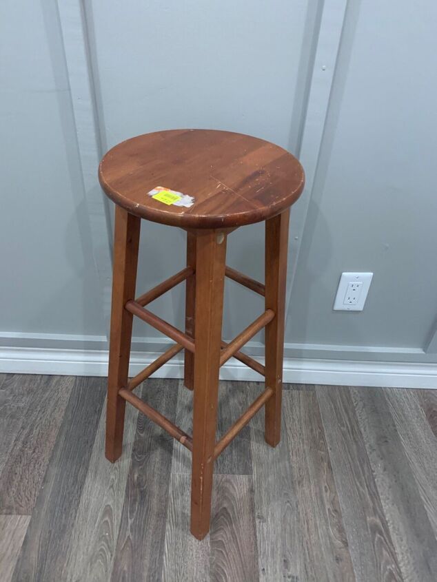 a small wooden stool sitting on top of a hard wood floor next to a wall