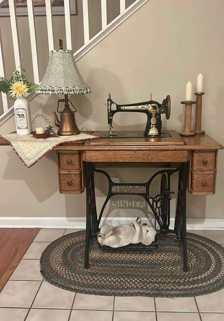 a sewing machine sitting on top of a wooden table next to a lamp and rug