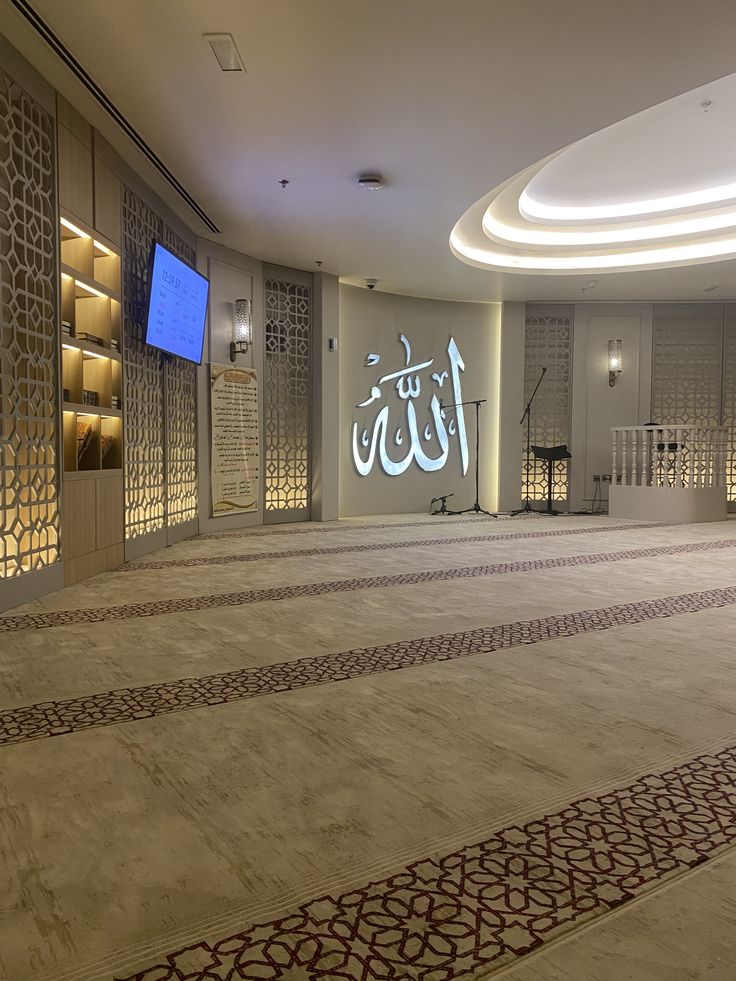 an empty room with arabic calligraphy on the walls and carpeted flooring in front of a large screen