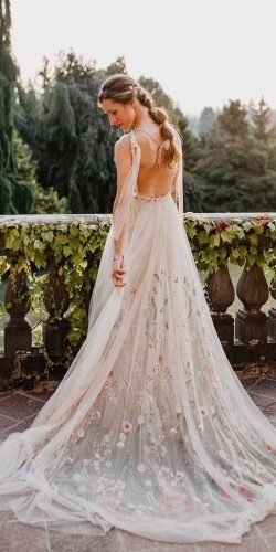 a woman wearing a wedding dress with flowers on it and her back to the camera