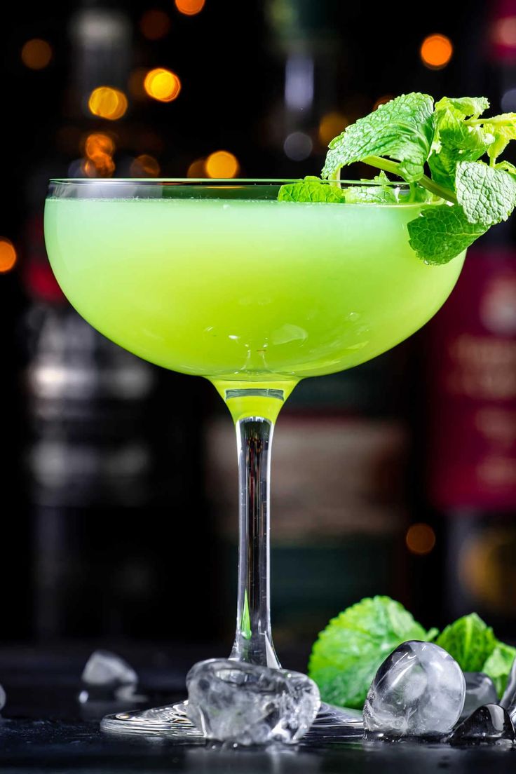 a green cocktail garnished with mint and ice