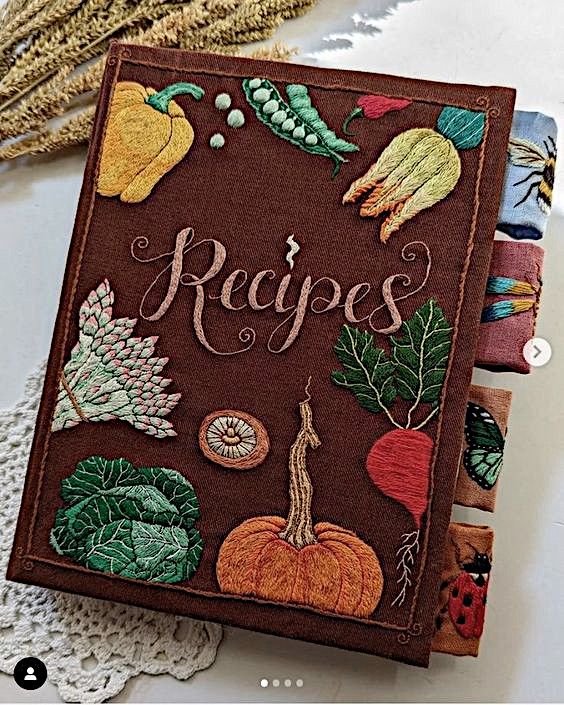 an embroidered recipe book sitting on top of a doily next to some other items