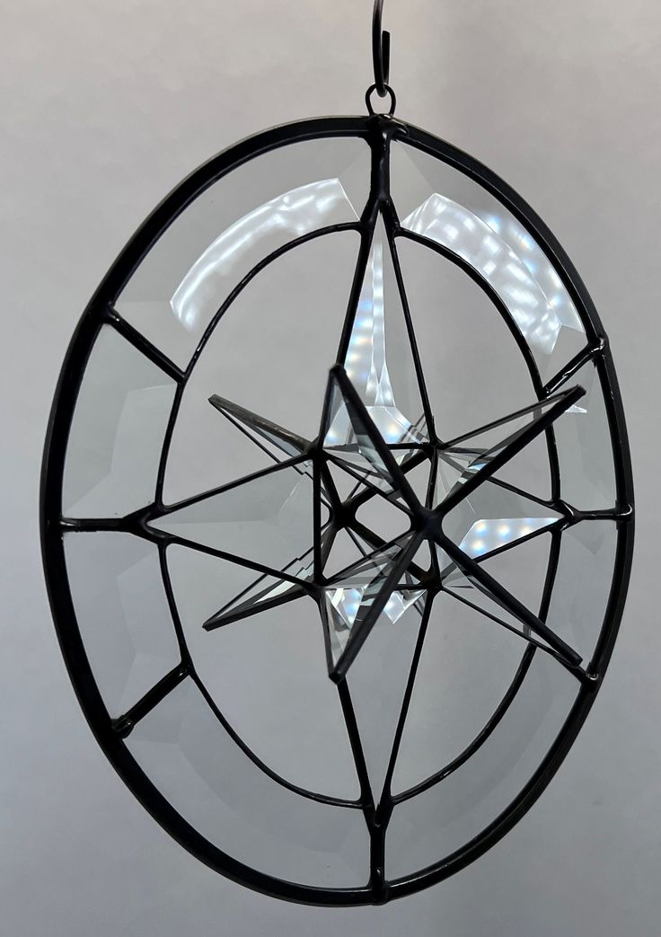 a glass and metal star ornament hanging from a chain on a white wall