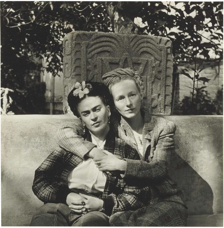 an old black and white photo of two people sitting on a couch with their arms around each other