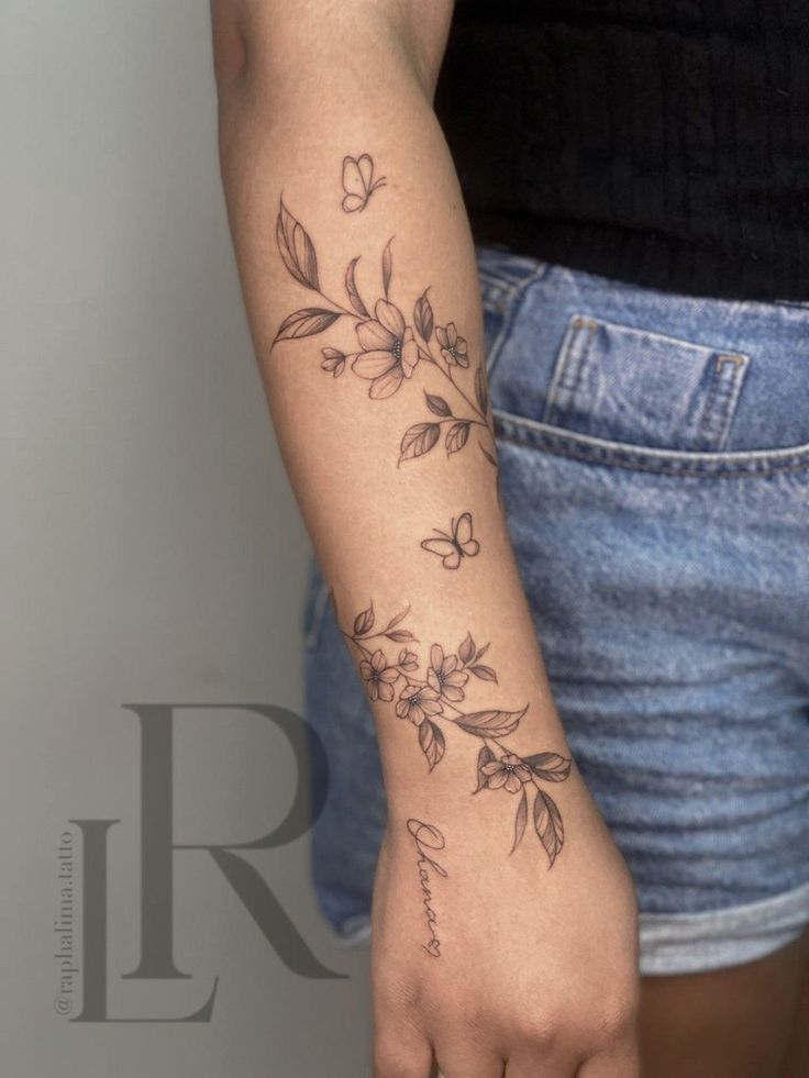 a woman's arm with flowers on it and the word love written in cursive writing